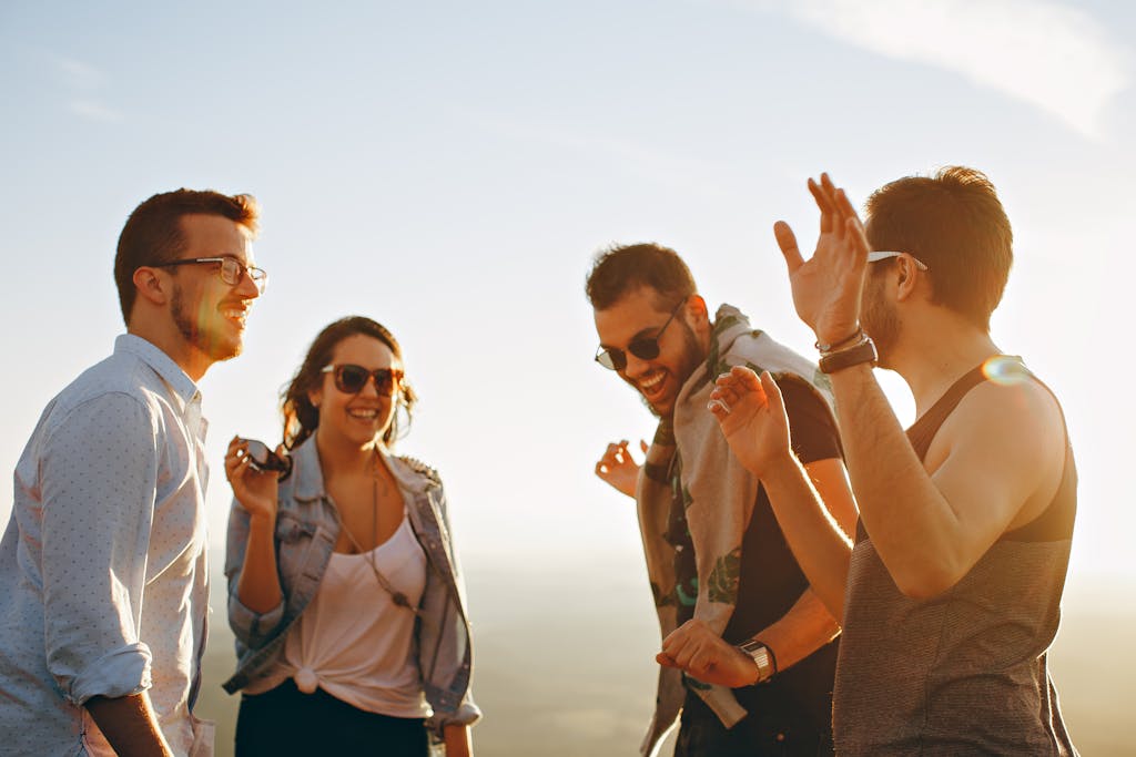 A group of friends laughing and dancing outdoors on a bright sunny day, showcasing friendship and joy.